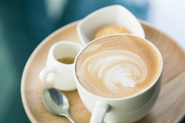 Kopje koffie met een schaal met koekjes en een theelepel