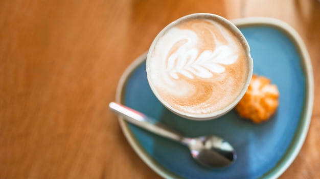 Kopje koffie met mooie latte kunst op houten tafel