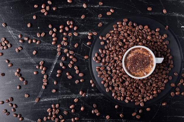 Kopje koffie op bruine korrels.