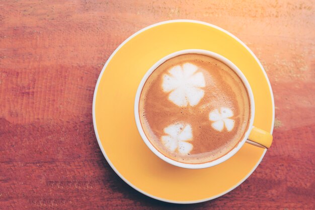 kopje koffie op houten tafel met bloem melk decoratie op de top van koffie oppervlak