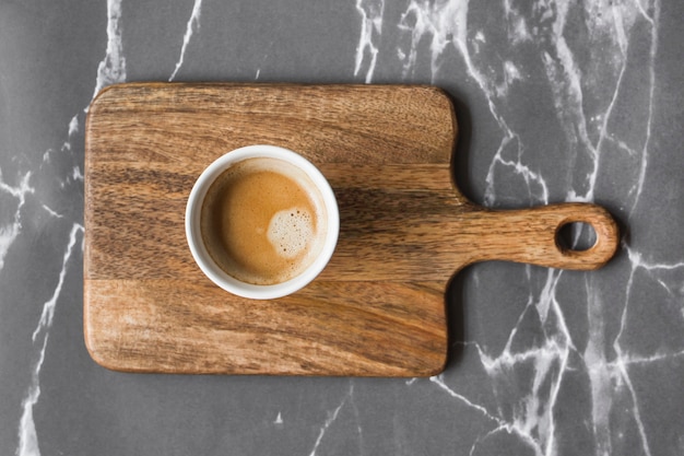 Gratis foto kopje koffie op snijplank over grijze marmeren achtergrond