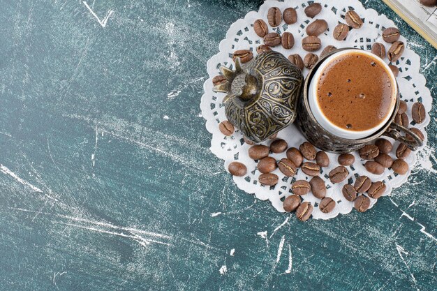 Kopje schuimende koffie en koffiebonen op marmeren oppervlak.