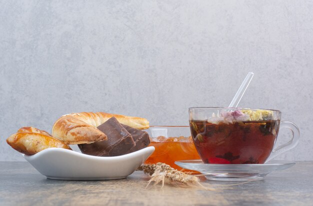 Kopje thee, koekjes en bessenjam op marmeren tafel.