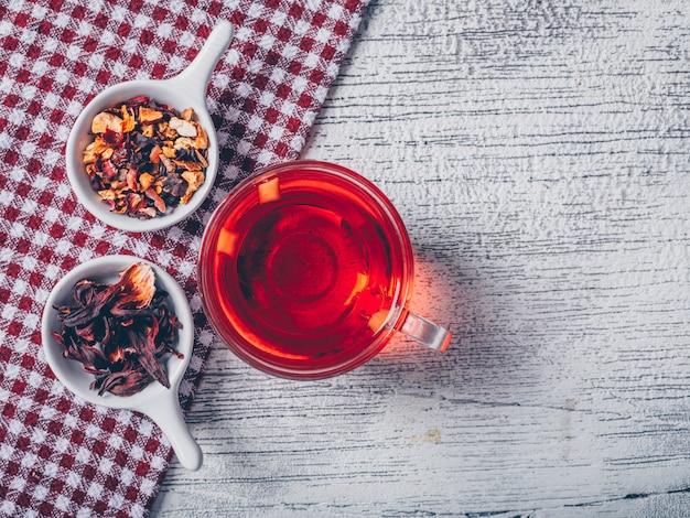 kopje thee met thee kruiden bovenaanzicht op een picknick doek en grijze houten achtergrond