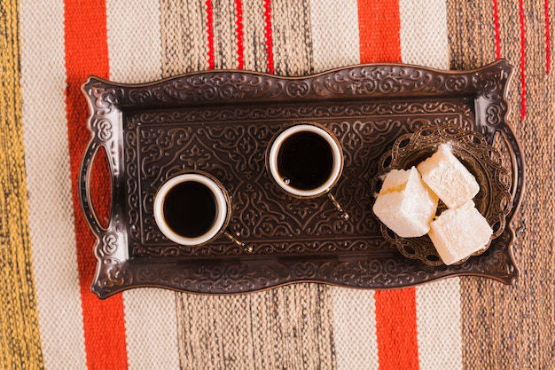 Kopjes koffie in de buurt van schotel met zoete Turkse lekkernijen op dienblad