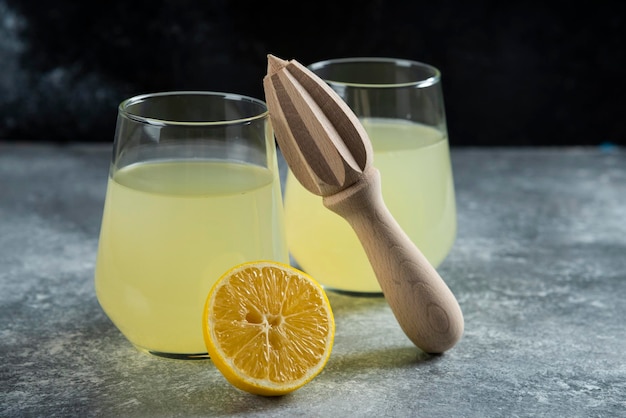 Kopjes limonade met schijfje citroen en houten ruimer.