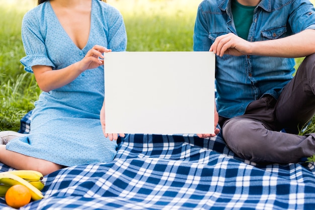 Gratis foto koppel met blanco papier zittend op de deken