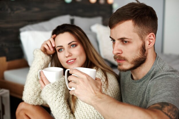 Koppel met koffie zittend op de vloer in de slaapkamer