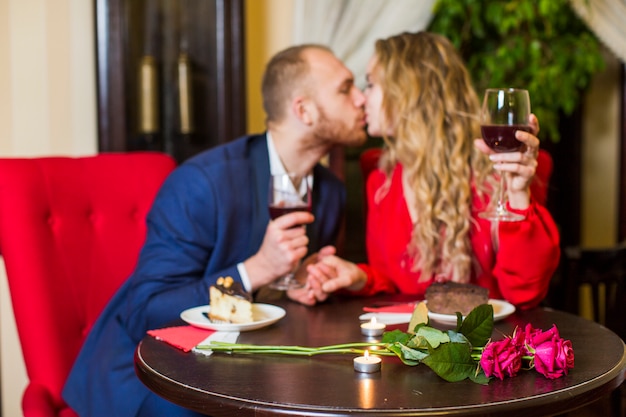 Gratis foto koppel met wijnglazen kussen aan tafel