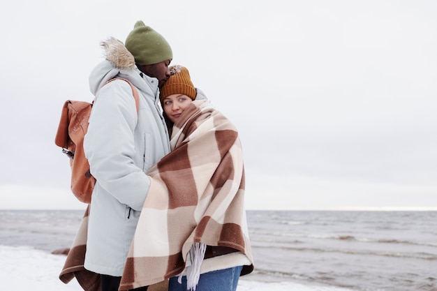 Gratis foto koppel wordt samen wakker aan het strand tijdens een winterse roadtrip