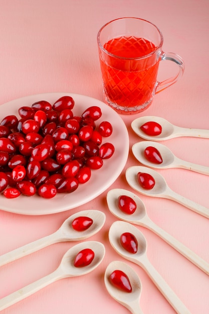 Kornoeljebessen in plaat en houten lepels met de mening van de drank de hoge hoek op roze