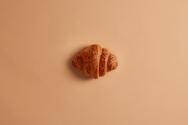 Korst heerlijke zoete boterachtige croissant voor ontbijt op bruine achtergrond. Versgebakken zoetwaren, lekker dessert, junkfood. Zelfgemaakt smakelijk bakkerijproduct voor zoetekauwen. Frans voedsel