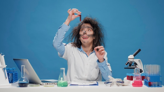 Krankzinnige dwaze vrouwelijke scheikundige die met de microscoop in de studio werkt, gek en krankzinnig doet op de camera. Goofy grappige vrouw die zich dom voelt en grappig is, gekke speelse wetenschapper met rommelig haar.