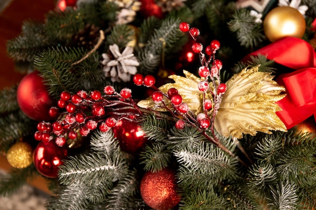 Krans gemaakt van kerstboomtakken en bulten, rode linten en rode bessen, gouden en rode ballen Premium Foto