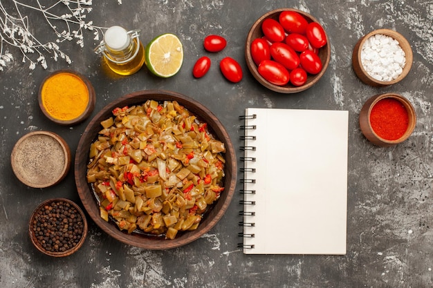 kruiden op tafel citroenfles olie kleurrijke kruiden en tomaten in de kommen naast het witte notitieboekje en boomtakken