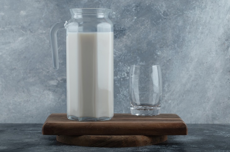 Gratis Foto kruik verse melk en glas water op een houten bord.