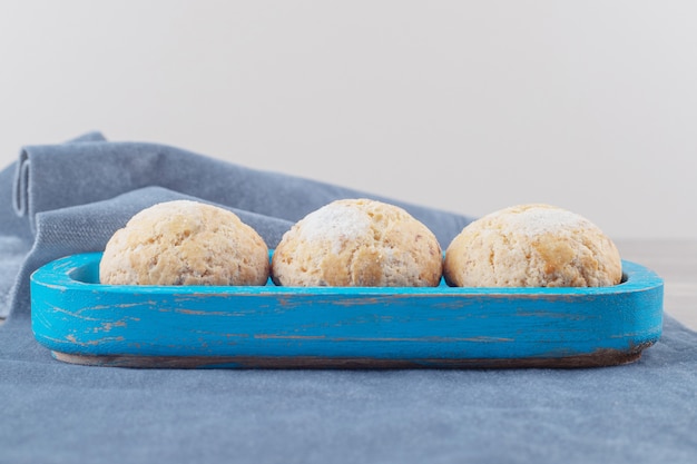 Kruimelige koekjes op een blauwe schaal op een stuk stof op marmer