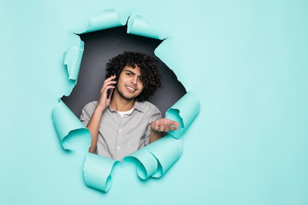 Krullend jongeman praten aan de telefoon van gat op Groenboek