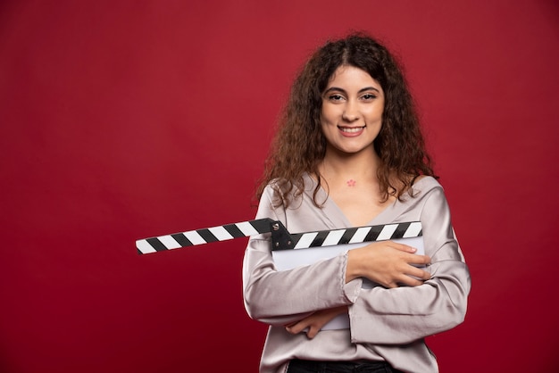 Gratis foto krullende haired vrouw met staande filmklapper.