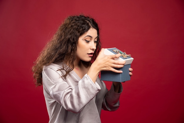 Krullende jonge vrouw die giftdoos controleert.