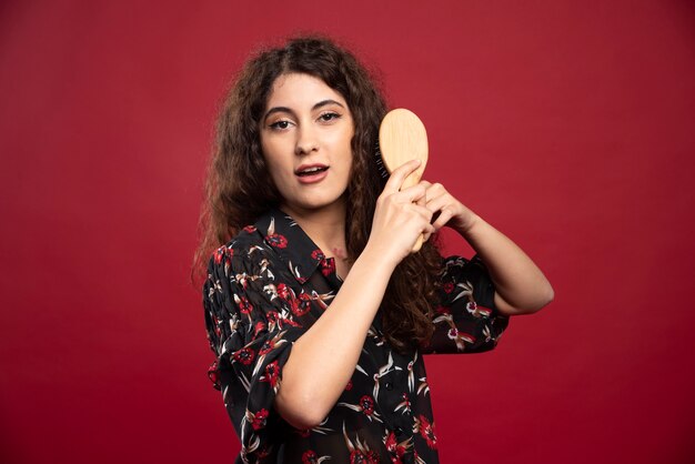 Krullende vrouw die haar haar kamt.