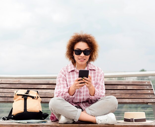 Krullende vrouw die haar telefoon op een bank controleert