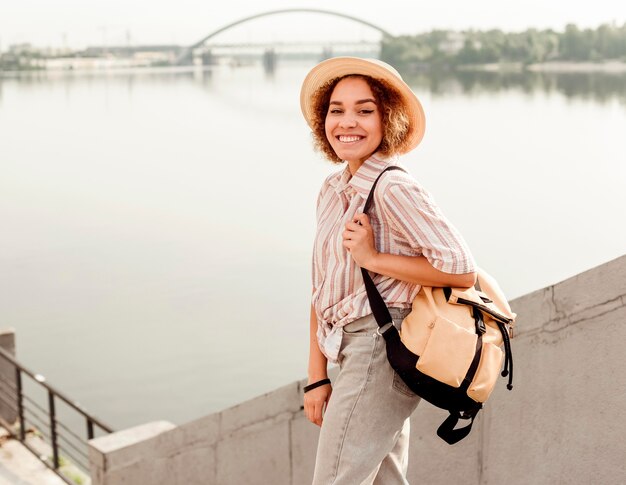 Krullende vrouw die lacht terwijl poseren naast een rivier