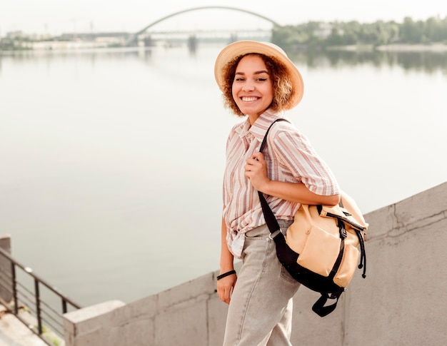 Krullende vrouw die lacht terwijl poseren naast een rivier