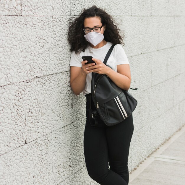 Krullende vrouw die medisch masker draagt