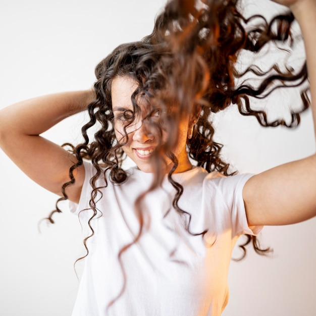 Gratis foto krullende vrouw die met haar haar speelt