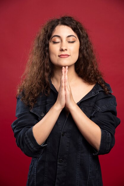 Krullende vrouw in denim jasje meditatie doen.