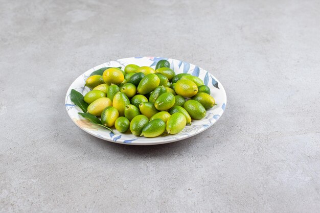 Kumquats en bladeren op een plaat op marmeren achtergrond. Hoge kwaliteit foto