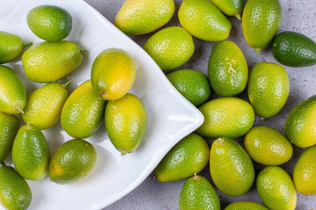 Kumquats op en rond een witte schotel op marmeren achtergrond. Hoge kwaliteit foto