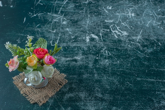 Kunstbloemen in een gieter, op de blauwe achtergrond.