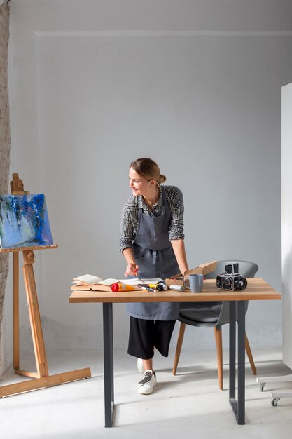 Kunstenaar in schort die aan bureau werkt