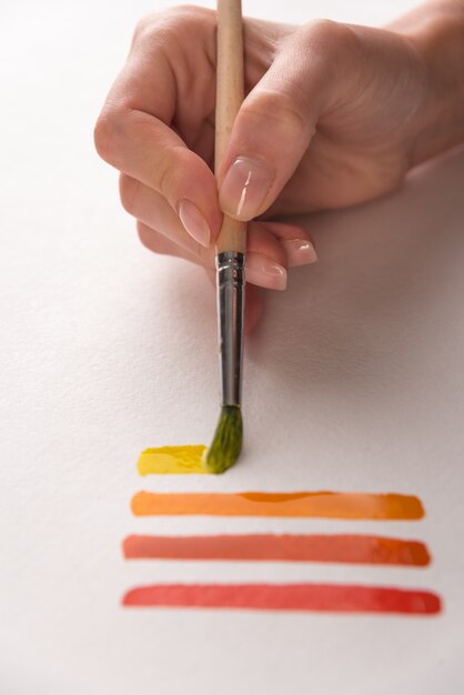 Kunstenaar kleurrijke strepen schilderen met penseel op wit papier