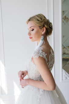 Kunstfoto van een zachtaardige mooie vrouw met blonde, bruid, prachtige dure witte jurk