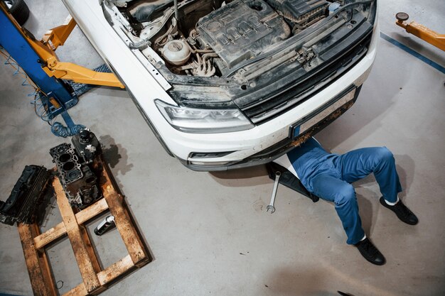 Kunstmatige verlichting. Werknemer in het blauw gekleurde uniform werkt in de autosalon