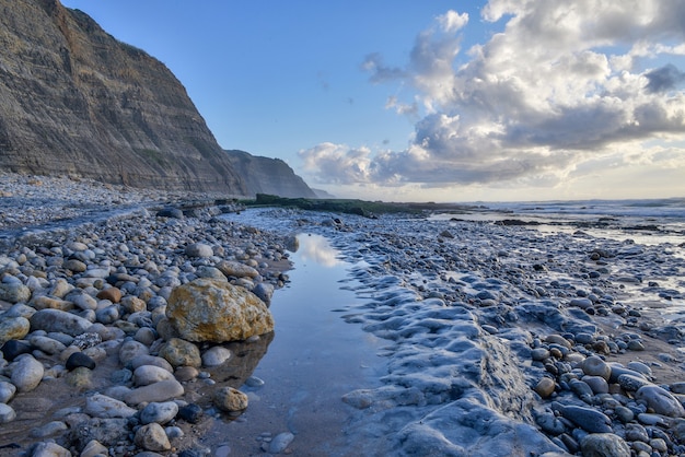 Kust omgeven door de zee en kliffen onder een bewolkte hemel tijdens de zonsopgang