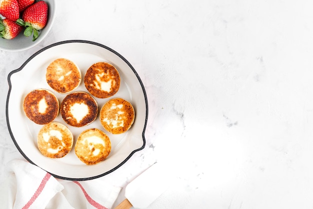 Kwark pannenkoeken cheesecakes ricotta beignets in een koekenpan met verse aardbeien Gezond en heerlijk ontbijt voor Valentijnsdag Bovenaanzicht een plek om te kopiëren