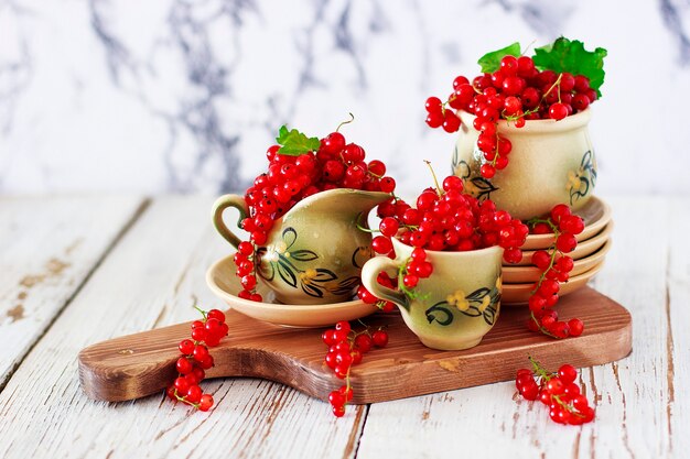 Kwarkkoekjesbroodjes met rode aalbessen op keramische plaat met vintage keramische thee of koffie set, theetijd, ontbijt, zomersnoepjes