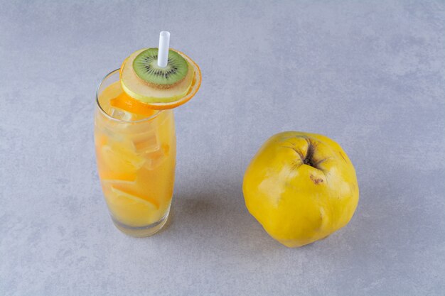 Kweepeer een glas sinaasappelsap op marmeren tafel.