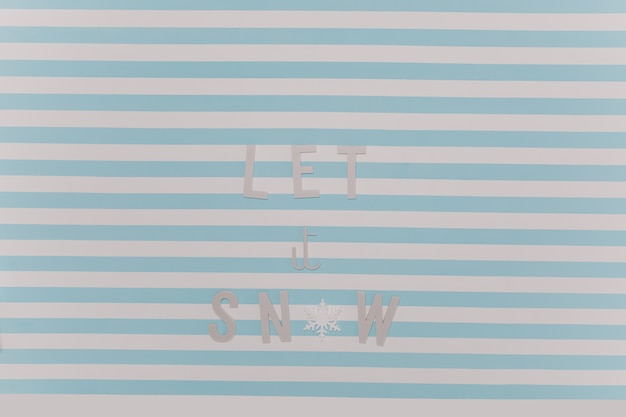 Laat het sneeuwen. Mooie Nieuwjaar winter inscriptie op wit en blauw gestreepte muur.