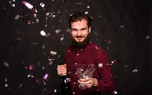 Lachen man met fles en glazen tussen confetti