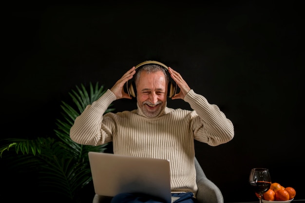 Lachend bejaard mannetje dat op hoofdtelefoon zet