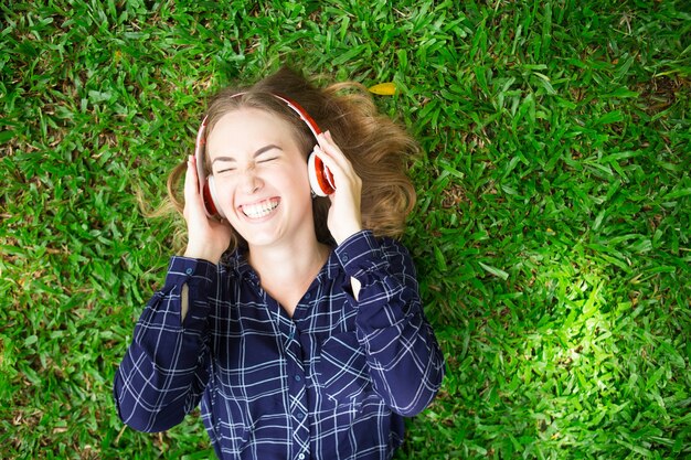 Lachend meisje geniet van luisteren naar muziek op gras