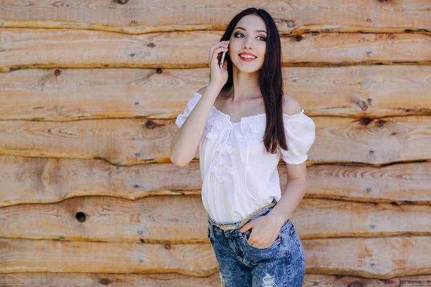 Lachend meisje leunend op een houten muur te praten over de telefoon