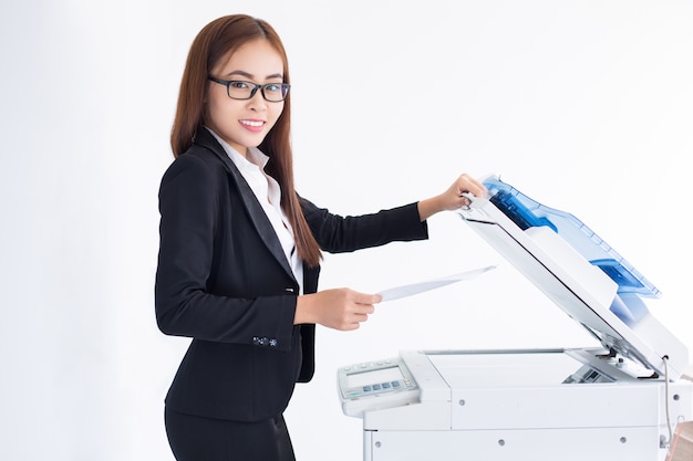 Gratis foto lachende aziatische zakenvrouw met behulp van copier machine