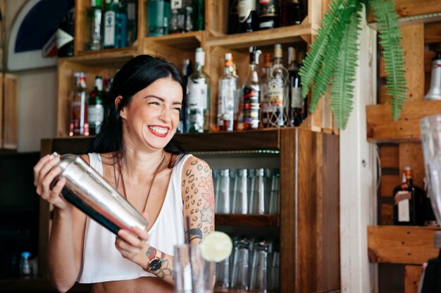 Lachende barman die een cocktail maakt