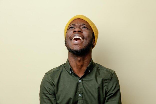 lachende jonge afro-amerikaanse man in hoed met een groen shirt geïsoleerd op een witte achtergrond